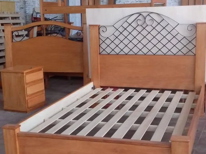 Cama de madera con respaldo trabajado y mesita de luz